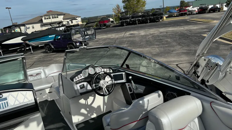 Slide: The Image of 2013 MasterCraft X55 boat interior with steering wheel and dashboard, parked outdoors. - 16