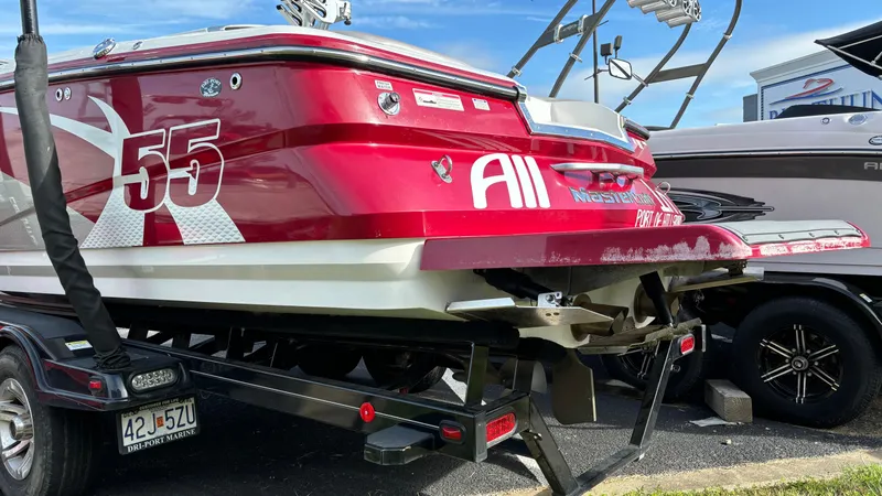 Slide: The Image of 2013 MasterCraft X55 boat in red on a trailer, parked outdoors. - 4
