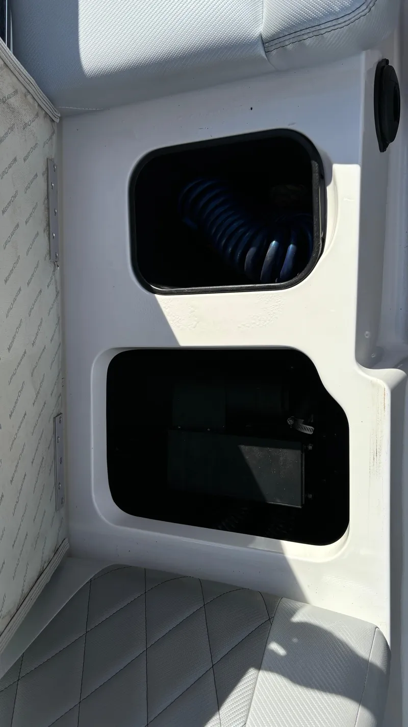 Slide: The Image of 2013 MasterCraft X55 boat storage compartments with coiled hose. - 46