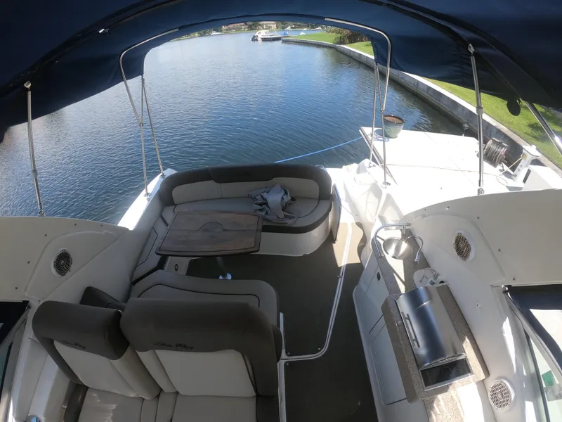 Slide: The Image of 2015 Sea Ray 330 Sundancer boat interior with seating and table on a calm waterway. - 10