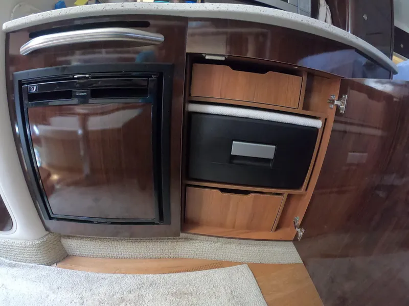 Slide: The Image of 2015 Sea Ray 330 Sundancer interior kitchen with fridge and storage cabinets. - 19