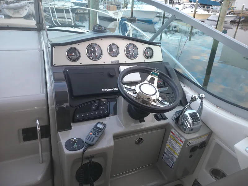 Slide: The Image of 2015 Sea Ray 330 Sundancer helm with steering wheel and control panel at marina. - 34