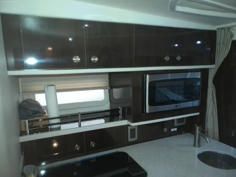 Slide: The Image of 2015 Sea Ray 330 Sundancer interior kitchen with dark wood cabinets and modern appliances. - 43