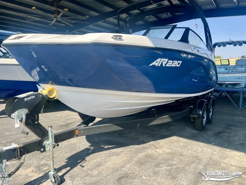 Slide: The Image of 2025 Yamaha Boats AR220, blue and white, on trailer in covered storage. - 1