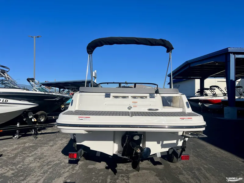 Slide: The Image of 2025 Bayliner VR5 boat, rear view, parked in marina under clear blue sky. - 2