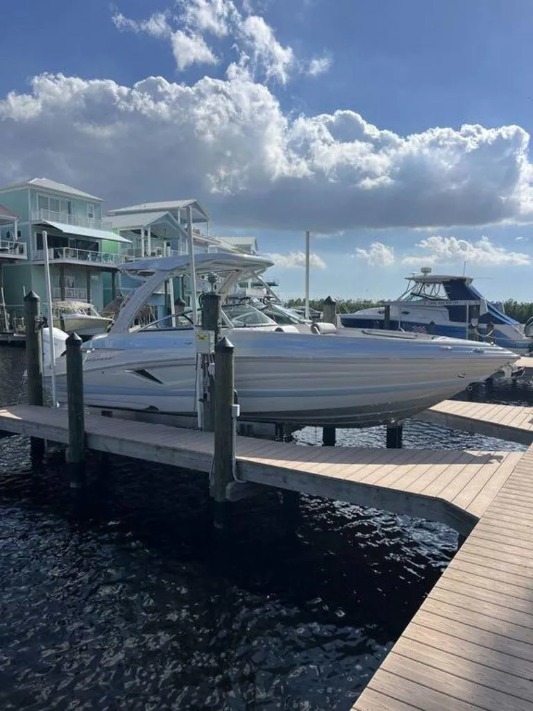 Slide: The Image of 2025 Crownline 290 XSS boat docked at marina under a partly cloudy sky. - 2