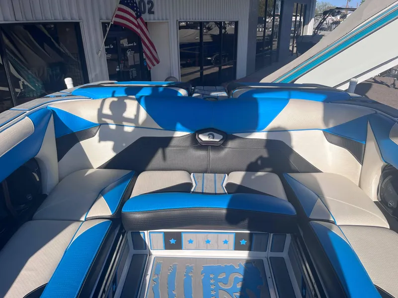 Slide: The Image of 2022 Centurion Ri265 boat interior with blue and white seating, American flag in background. - 12