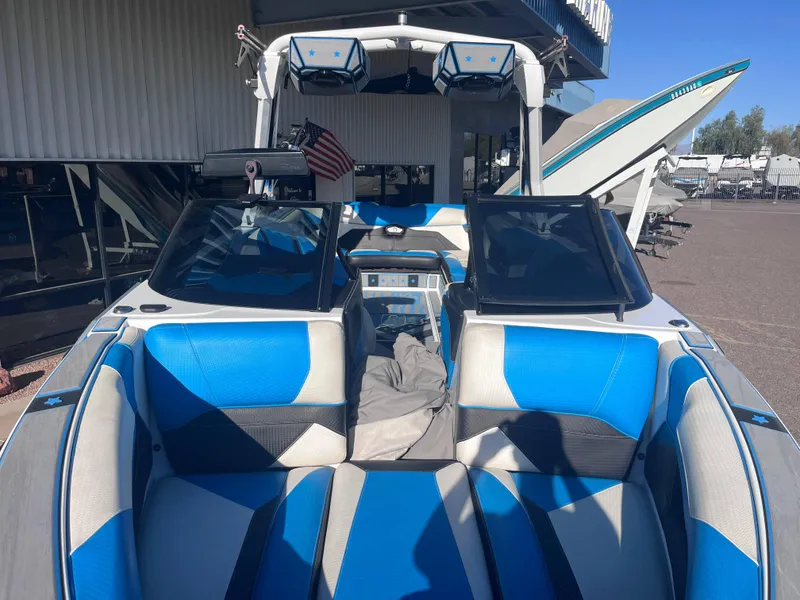 Slide: The Image of 2022 Centurion Ri265 boat interior with blue and white seating, docked outdoors. - 17