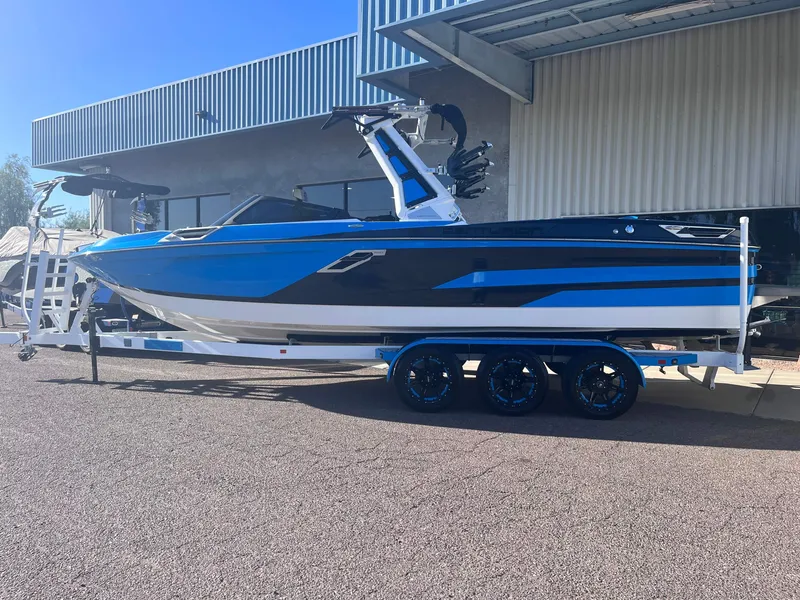 Slide: The Image of 2022 Centurion Ri265 boat on trailer, blue and black design, parked outdoors. - 2