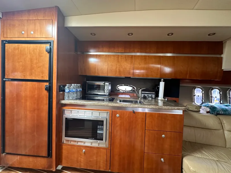 Slide: The Image of 2009 Cruisers Yachts 420 Express kitchen with wood cabinets, microwave, and refrigerator. - 23