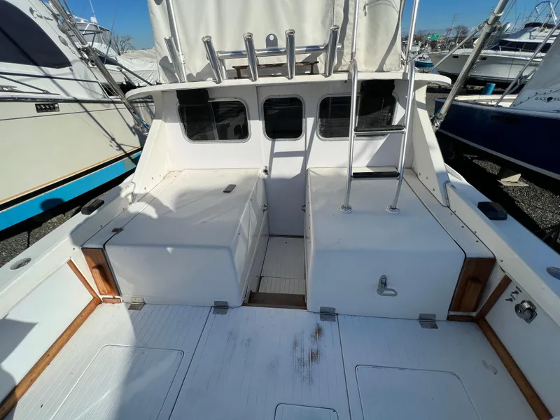 Slide: The Image of 1973 Bertram 31 Flybridge Cruiser, spacious deck, white exterior, docked in marina. - 17