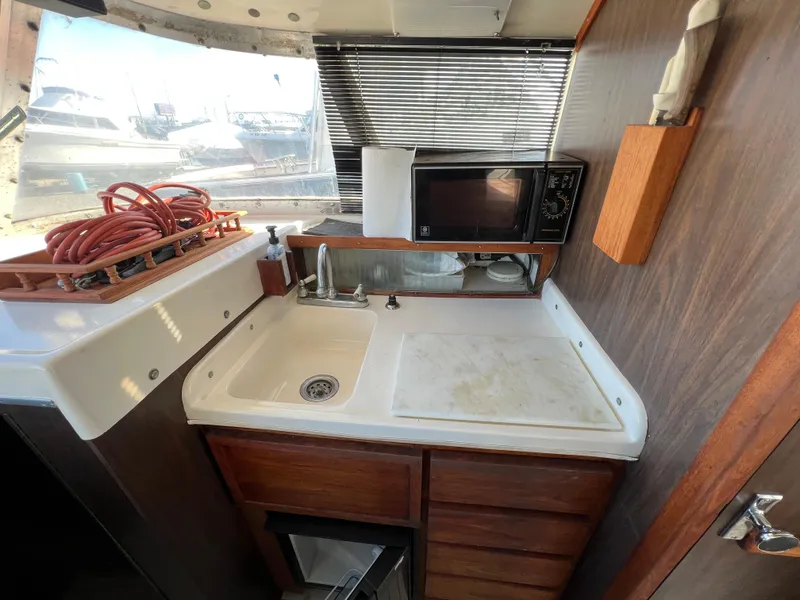 Slide: The Image of 1973 Bertram 31 Flybridge Cruiser kitchen with sink, microwave, and storage. - 20