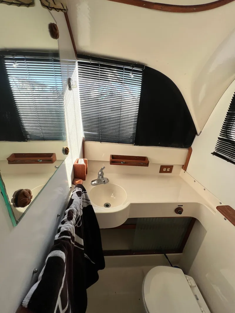 Slide: The Image of 1973 Bertram 31 Flybridge Cruiser bathroom with sink, mirror, and window blinds. - 21