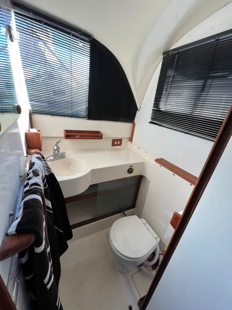 Slide: The Image of 1973 Bertram 31 Flybridge Cruiser bathroom with sink, toilet, and window blinds. - 22