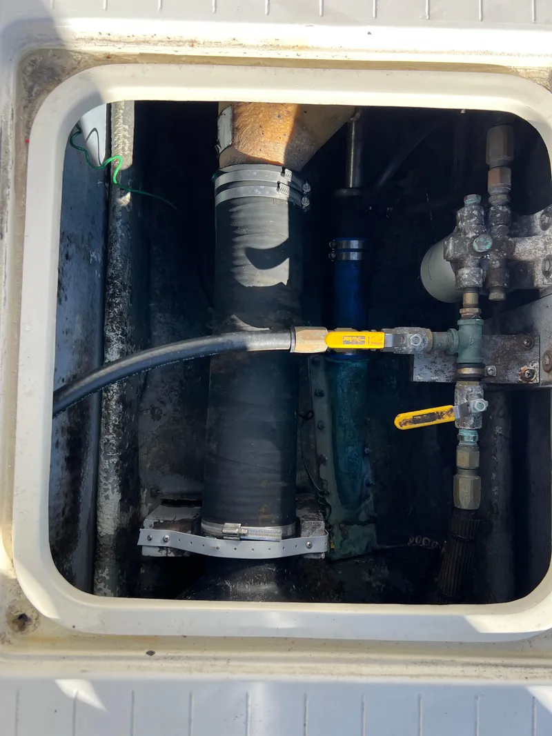 Slide: The Image of Engine compartment of 1973 Bertram 31 Flybridge Cruiser with visible hoses and valves. - 33