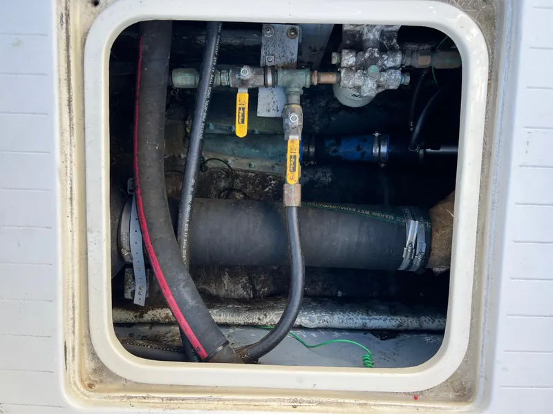 Slide: The Image of Engine compartment of a 1973 Bertram 31 Flybridge Cruiser with visible hoses and valves. - 34