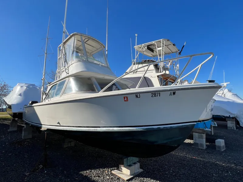 Slide: The Image of 1973 Bertram 31 Flybridge Cruiser on dry dock, clear blue sky background. - 6