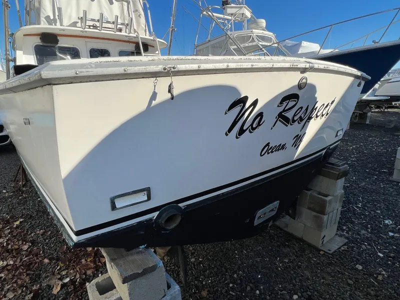 Slide: The Image of 1973 Bertram 31 Flybridge Cruiser on blocks, named "No Respect," in a boatyard. - 9