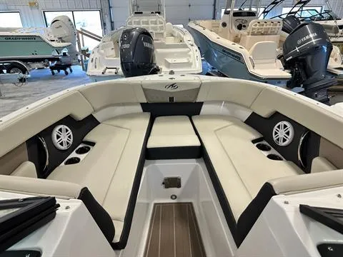 Slide: The Image of 2023 Monterey M-225 boat interior with beige seating and cup holders in showroom. - 7