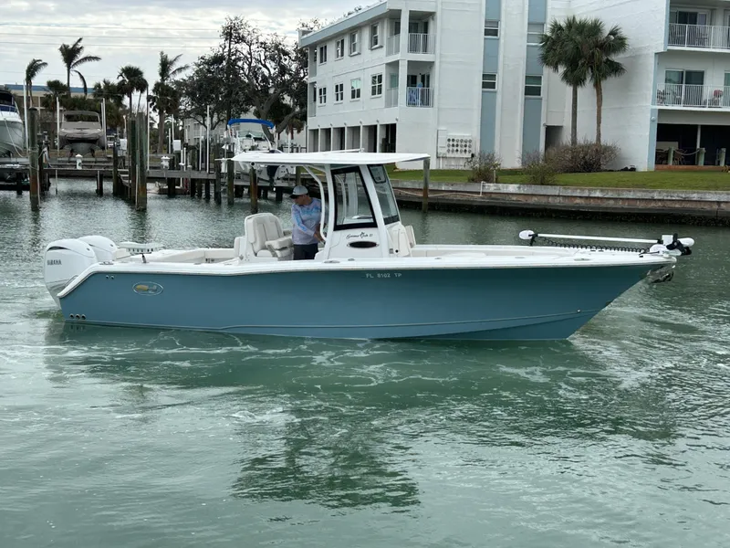Slide: The Image of 2024 Sea Hunt Gamefish 27 boat with Coffin Box cruising near waterfront buildings. - 1