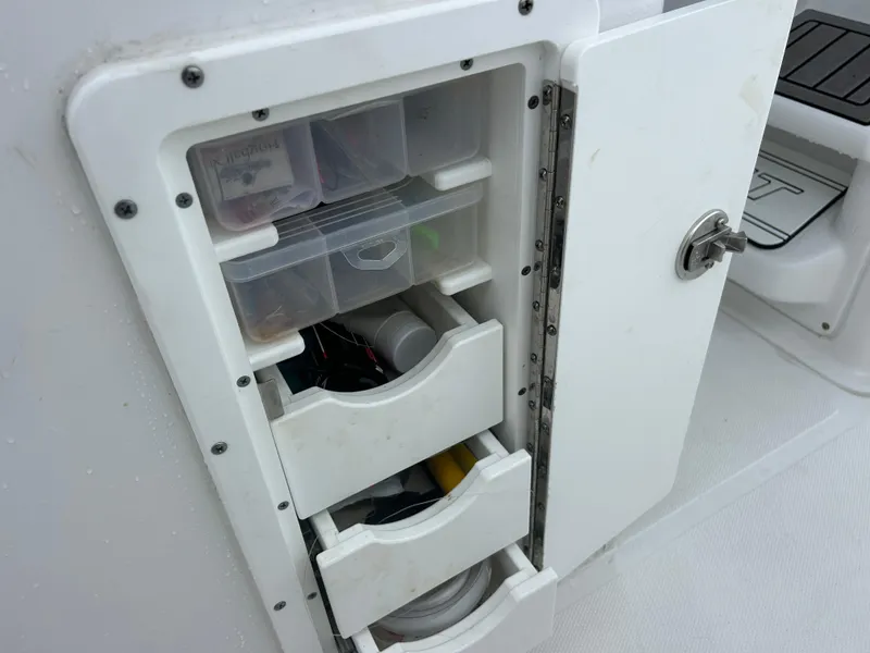 Slide: The Image of 2024 Sea Hunt Gamefish 27 storage compartment with organized tackle boxes and gear. - 38