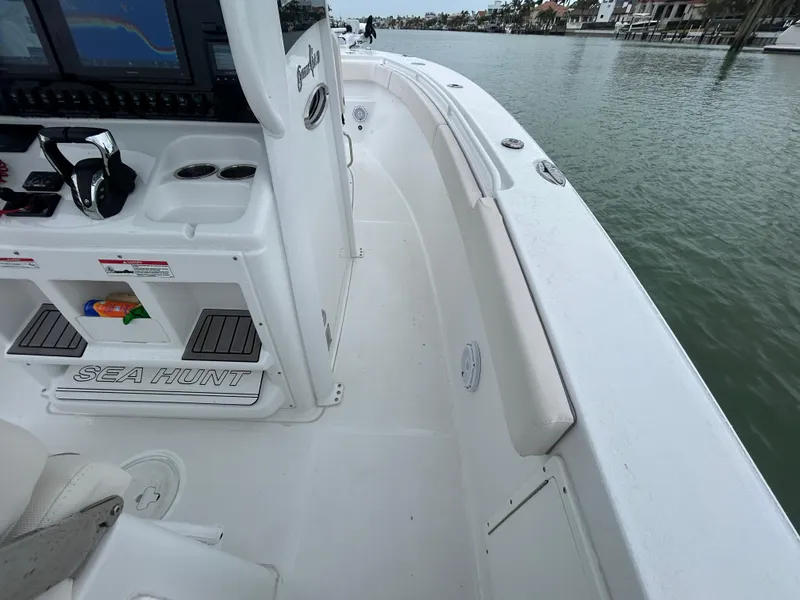 Slide: The Image of 2024 Sea Hunt Gamefish 27 boat deck with coffin box, docked by calm waters. - 9