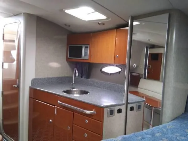 Slide: The Image of 2005 Formula 31 Performance Cruiser interior with kitchenette, featuring sink, microwave, and wooden cabinetry. - 27