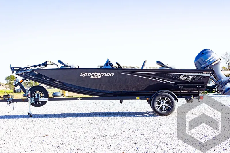 Slide: The Image of 2025 G3 Sportsman 1610 boat on trailer, sleek black design, parked on gravel. - 18