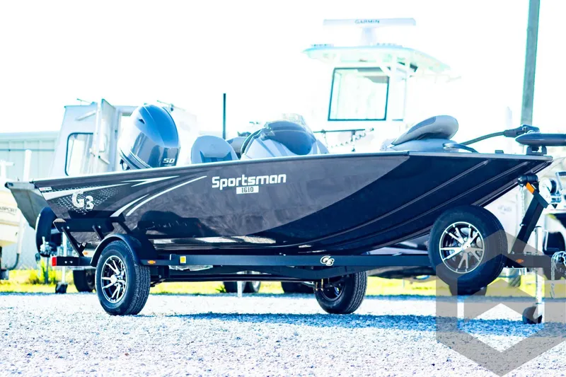 Slide: The Image of 2025 G3 Sportsman 1610 boat on trailer, sleek black design, parked outdoors. - 3