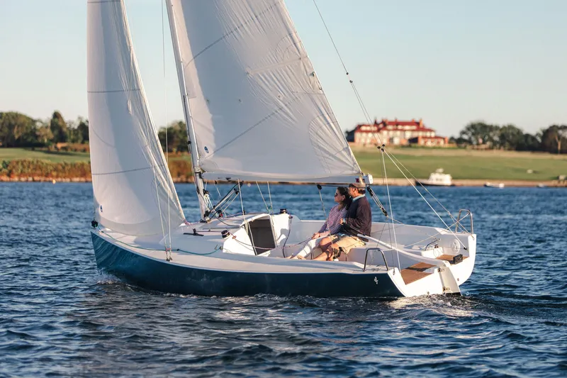 Slide: The Image of 2026 J Boats J/7 sailing on a serene lake with a scenic backdrop. - 2