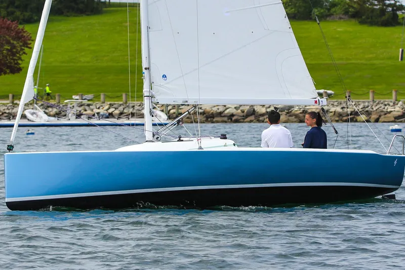 Slide: The Image of 2026 J Boats J/7 sailboat on water with two people, green shoreline background. - 5