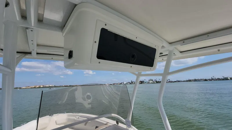 Slide: The Image of 2014 Striper 220 Center Console boat on calm water, featuring a clear windshield and overhead storage. - 25