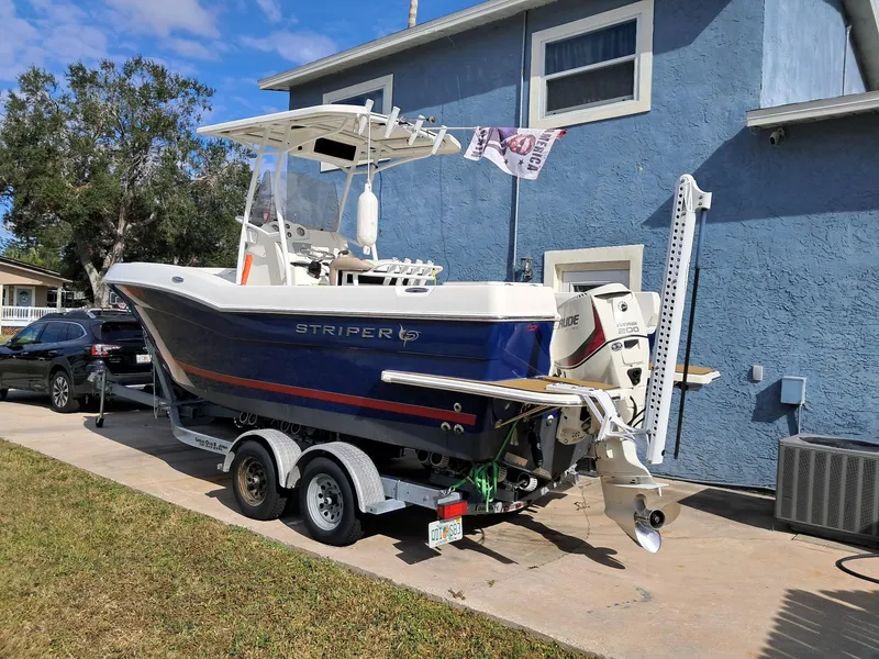 Slide: The Image of 2014 Striper 220 Center Console boat on trailer beside blue house. - 7