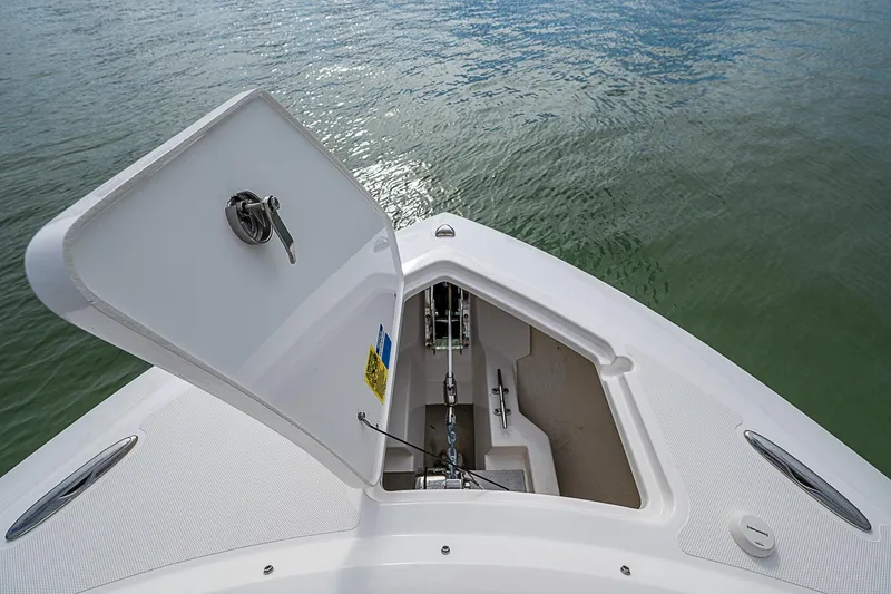 Slide: The Image of 2023 Pursuit DC 295 Dual Console boat anchor compartment open on calm water. - 14