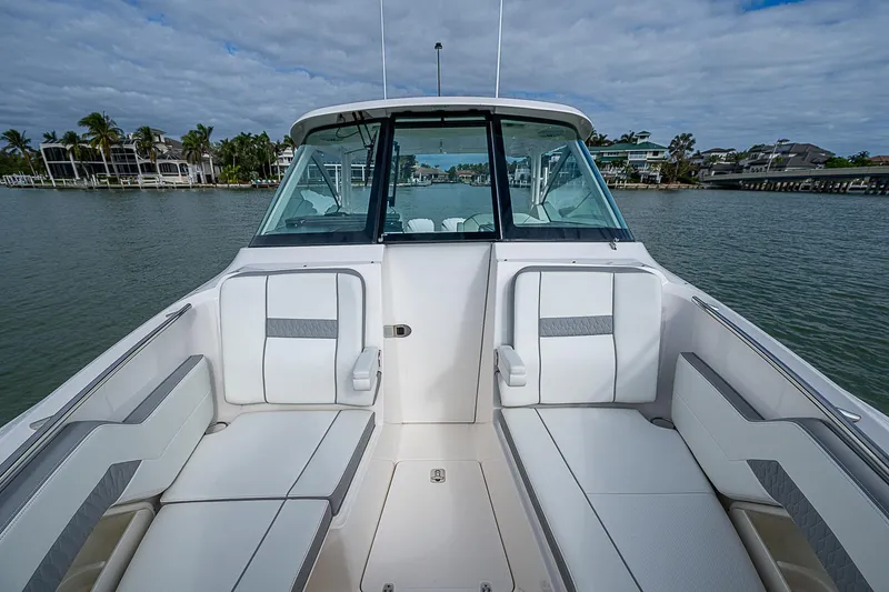 Slide: The Image of 2023 Pursuit DC 295 Dual Console boat interior with spacious seating on a calm lake. - 15