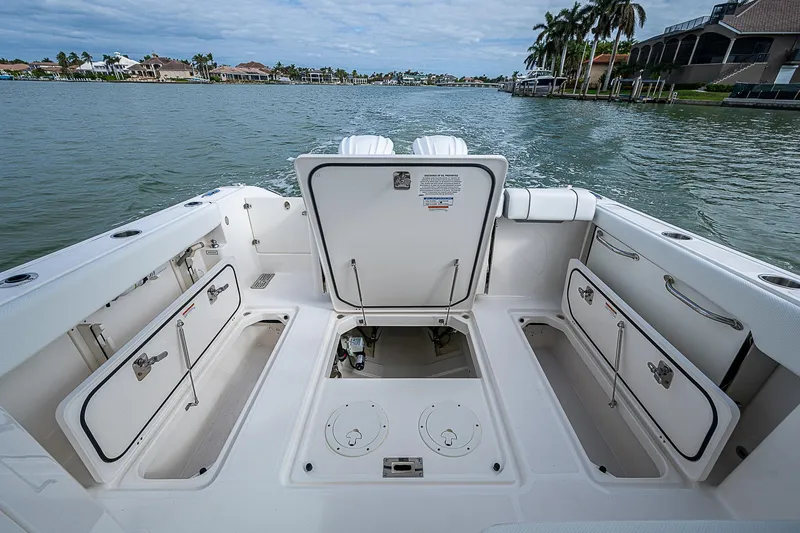 Slide: The Image of 2023 Pursuit DC 295 Dual Console boat with open storage compartments on a calm lake. - 25