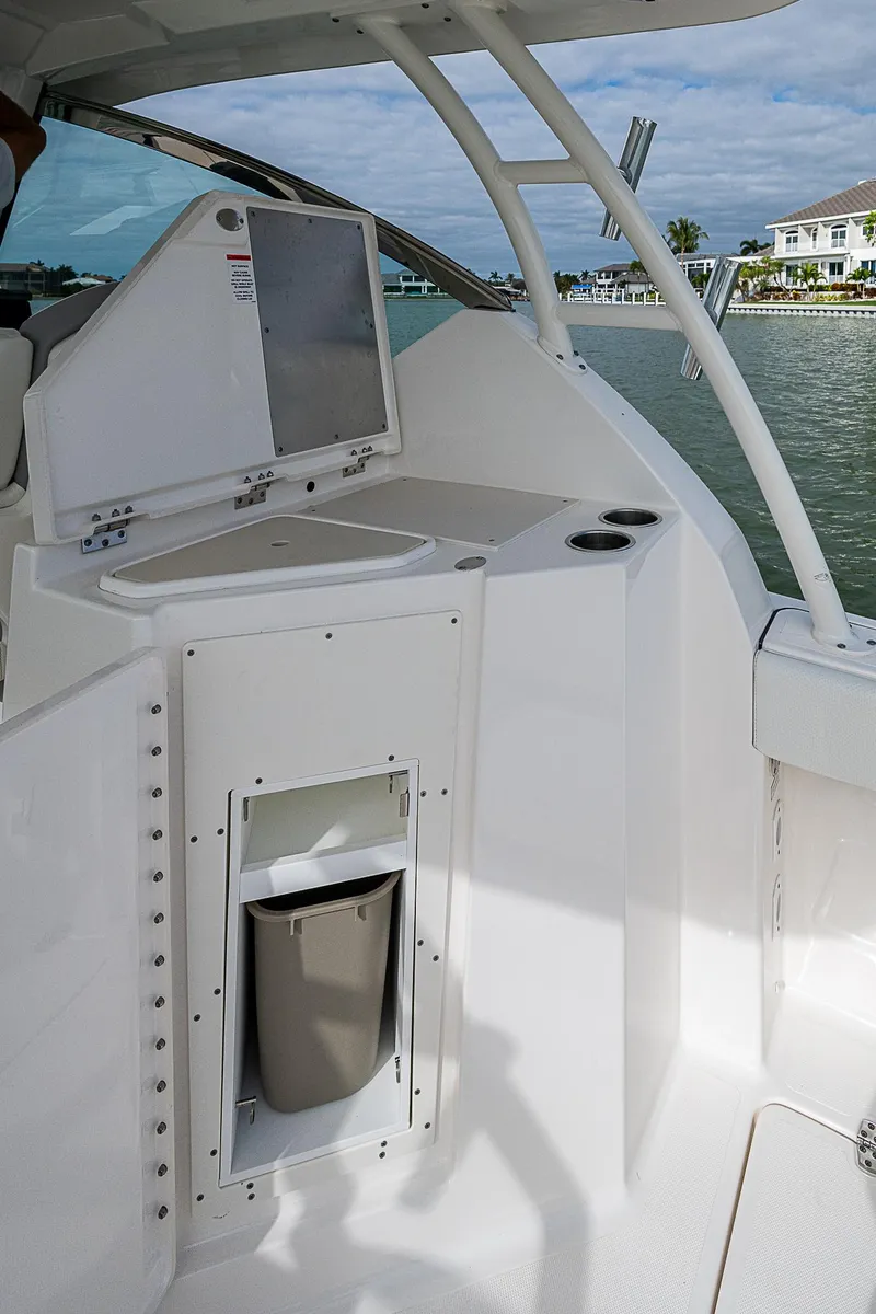 Slide: The Image of 2023 Pursuit DC 295 Dual Console boat interior with storage compartment and water view. - 27