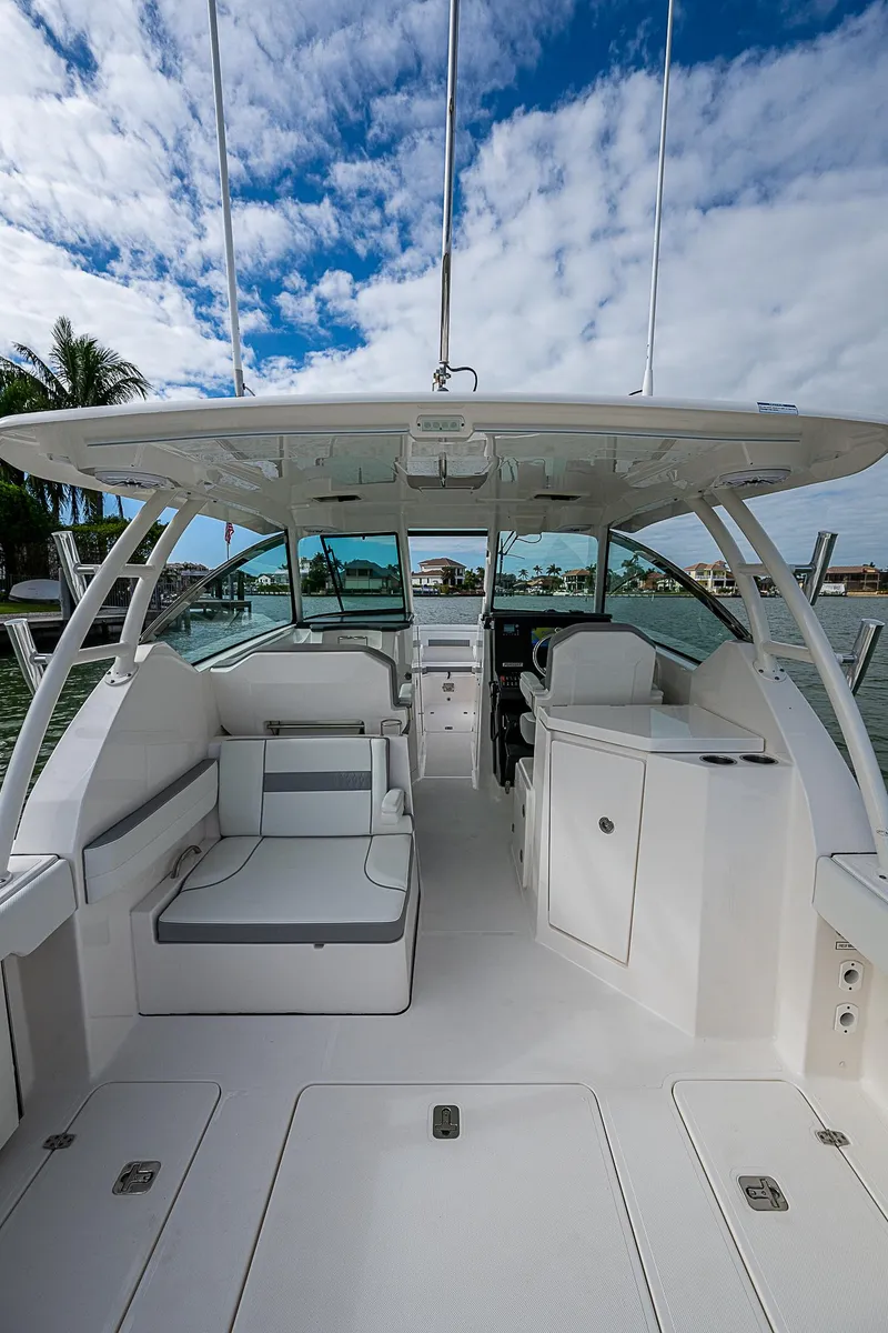 Slide: The Image of 2023 Pursuit DC 295 Dual Console boat interior with seating and helm, under a blue sky. - 29