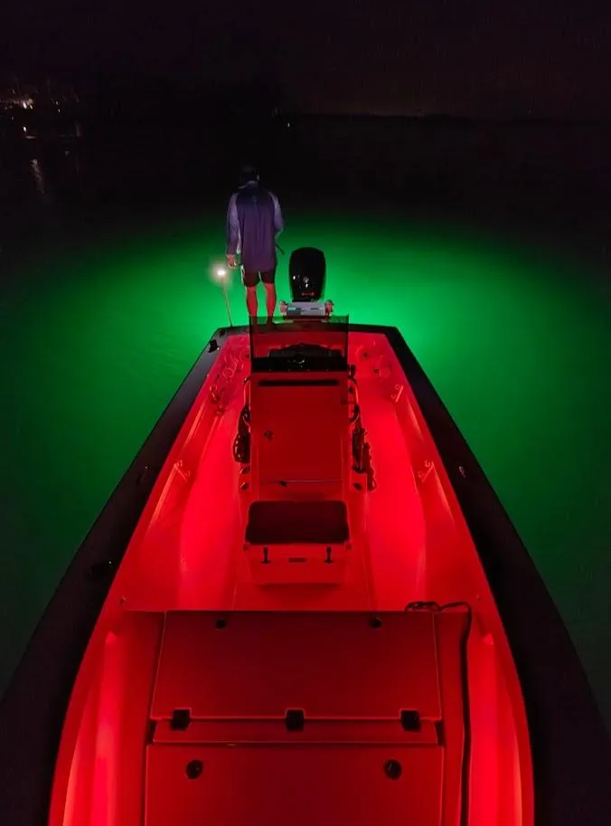 Slide: The Image of 2025 Cuda Craft 19 boat with vibrant red and green LED lights at night. - 14