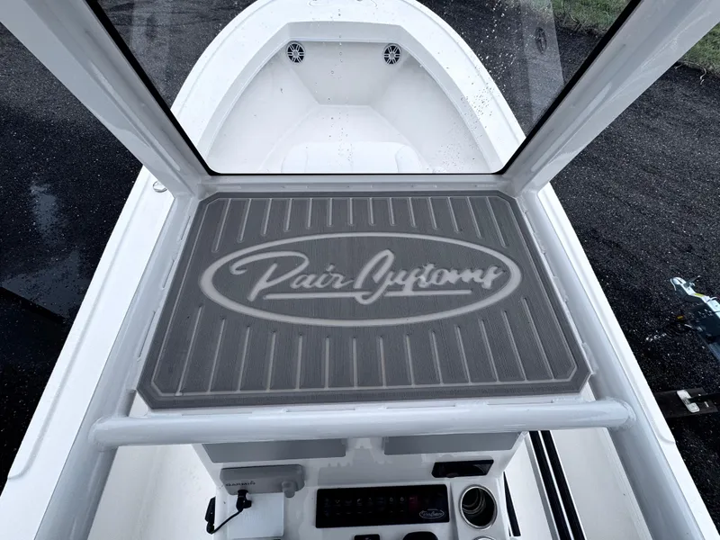 Slide: The Image of 2025 Pair Customs 24DV boat deck with branded mat and console view. - 17