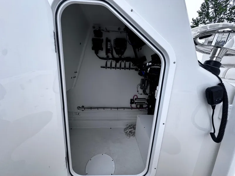 Slide: The Image of 2025 Pair Customs 24DV boat interior storage compartment with visible equipment and wiring. - 12