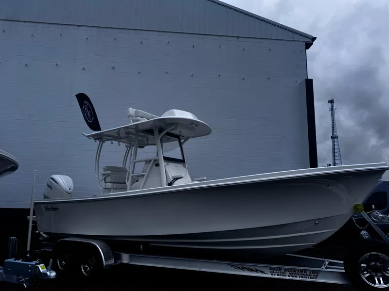 Slide: The Image of 2025 Pair Customs 24DV boat on trailer, parked near a large building. - 5