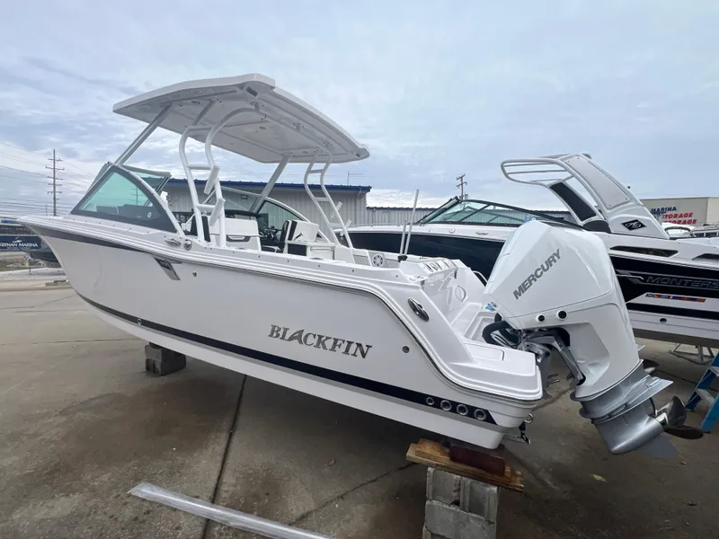 Slide: The Image of 2024 Blackfin 252 DC boat with Mercury engine, displayed outdoors. - 2