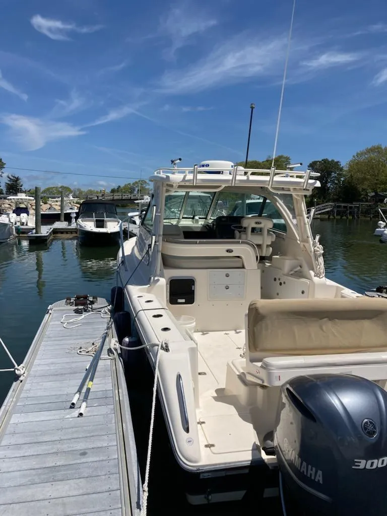 Slide: The Image of 2012 Pursuit 315 Offshore boat docked with Yamaha engine, clear sky background. - 10