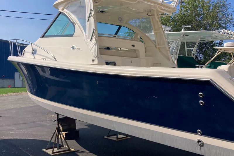 Slide: The Image of 2012 Pursuit 315 Offshore boat on stands, blue hull, outdoor display. - 5