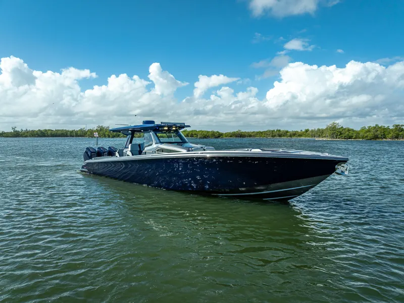 Slide: The Image of 2024 Nor-Tech 450 Sport Center Console boat on calm water under blue sky. - 15