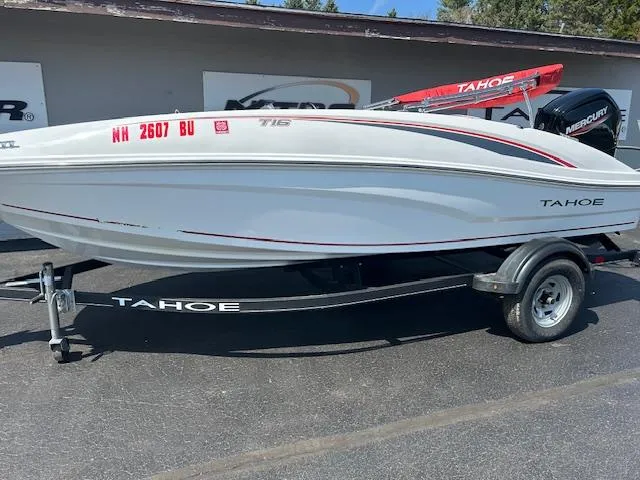 Slide: The Image of 2022 Tahoe T16 boat on trailer, white with red accents, parked outdoors. - 8