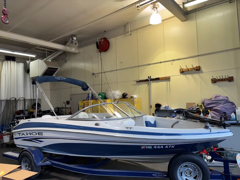 Slide: The Image of 2006 Tahoe Q4 Sport boat in a garage, blue and white design, on a trailer. - 2