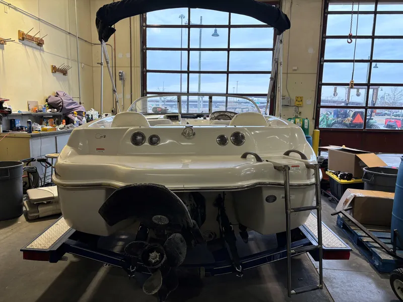 Slide: The Image of 2006 Tahoe Q4 Sport boat in a workshop, rear view with visible propeller and ladder. - 4