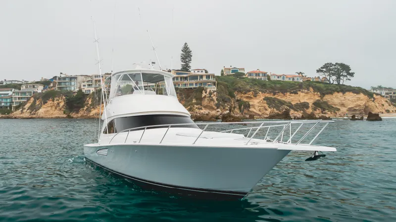 Slide: The Image of 2017 Viking 48 Convertible yacht on calm waters near a scenic coastline. - 2